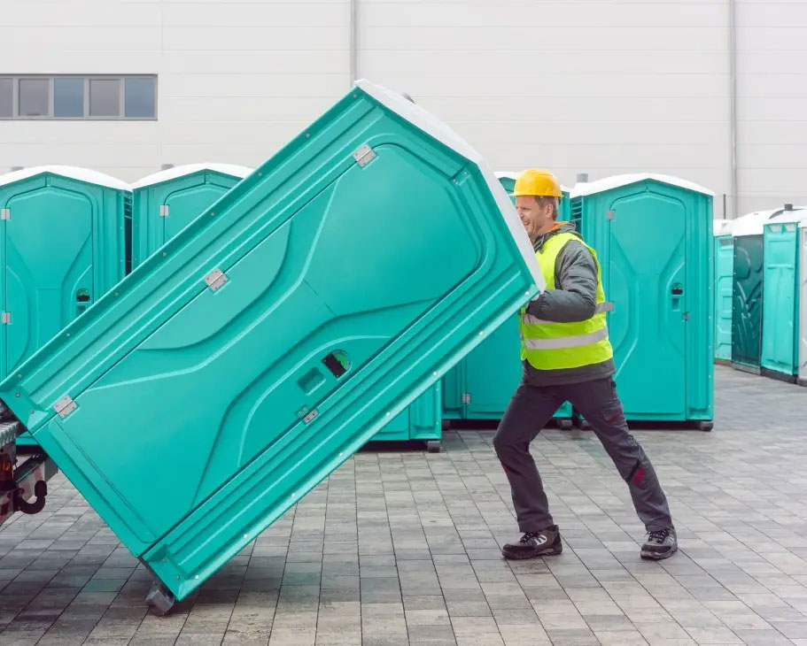 Worker unloading porta-potty.