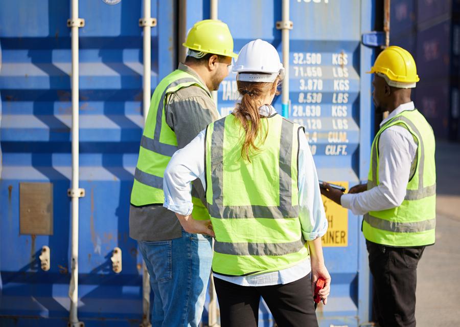 Workers in front of a shipping container at a work site.