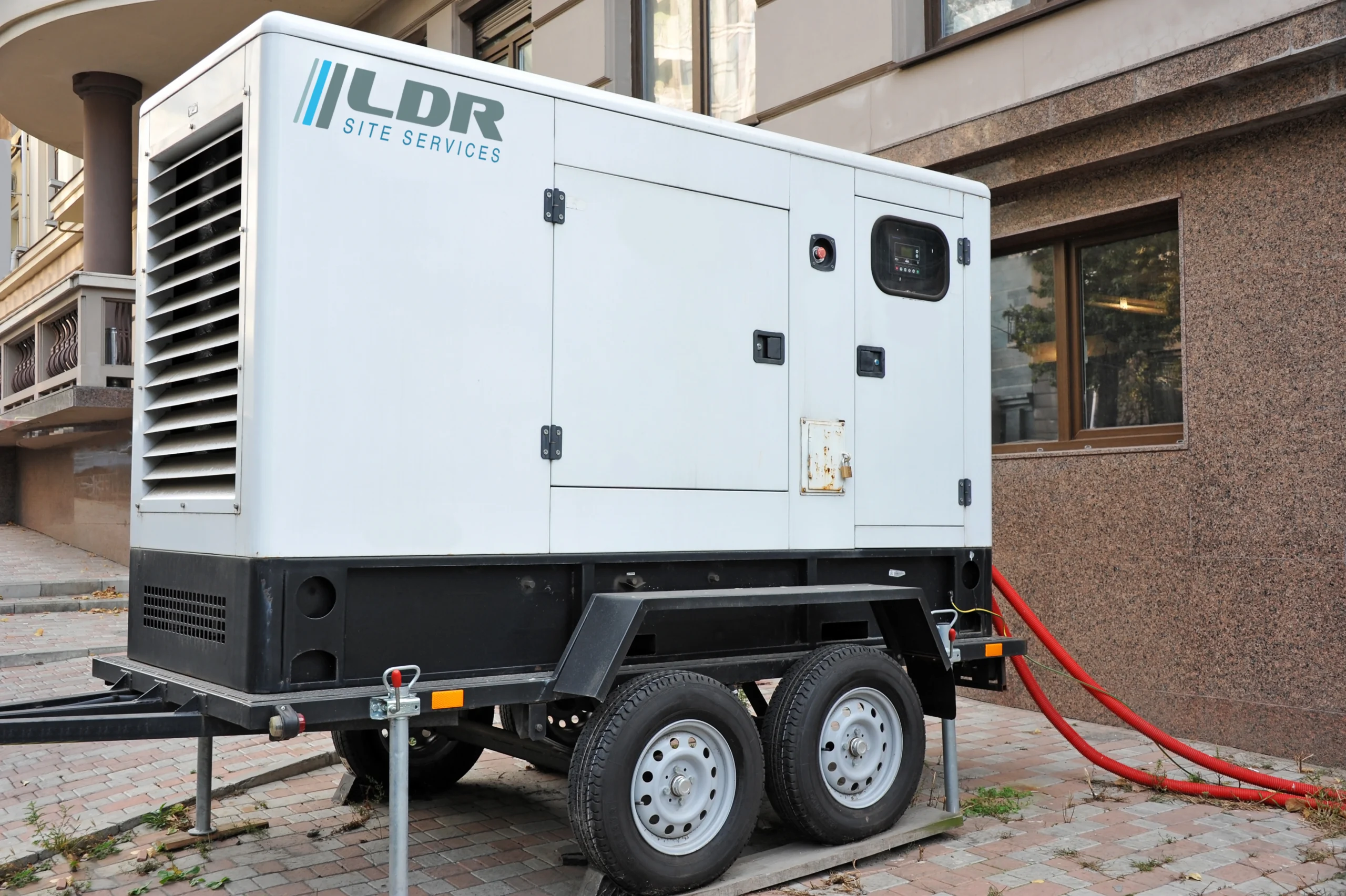 LDR Site Services towable diesel generator connected outside a commercial building for backup power