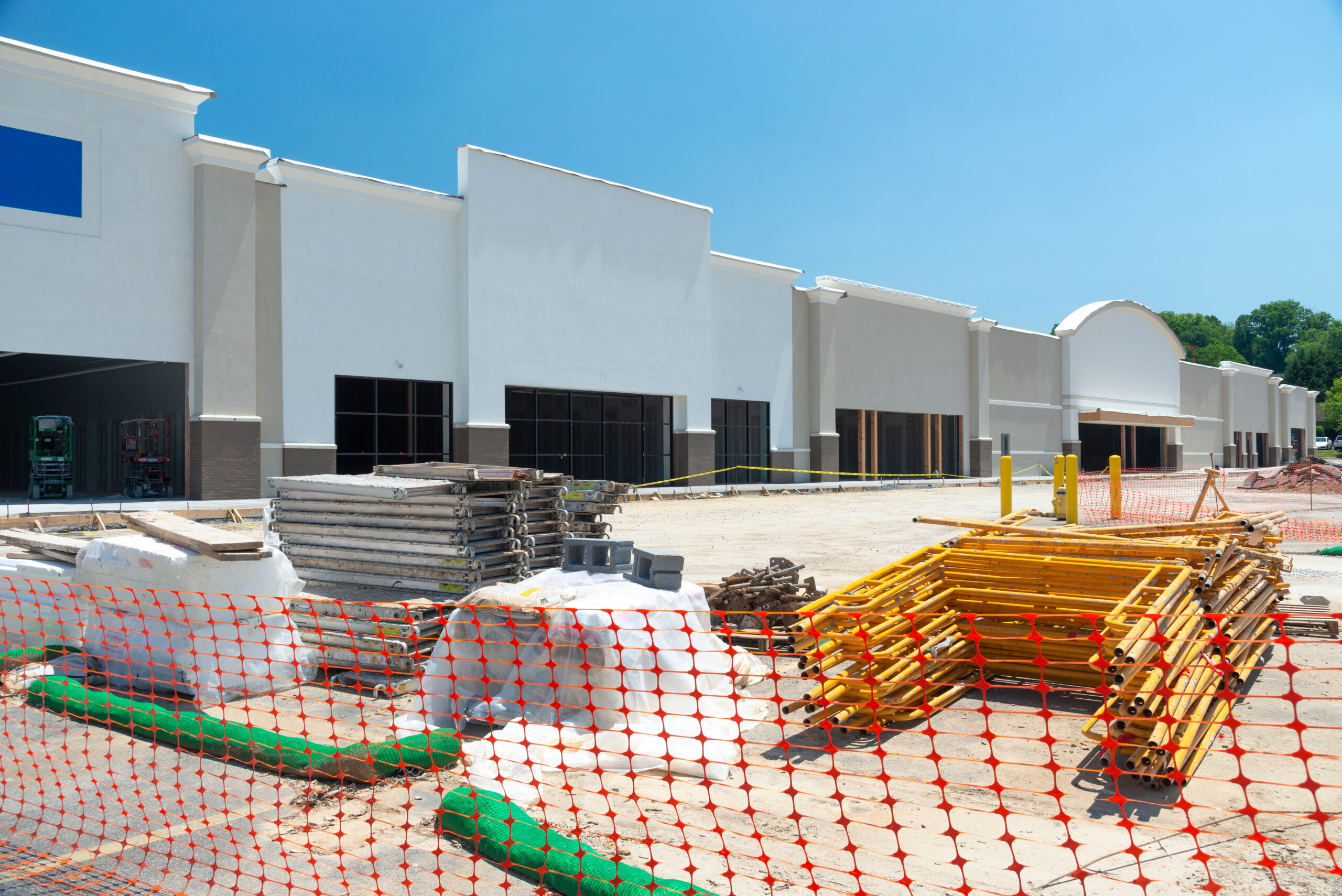 A roll-off dumpster and a compactor staged on the service apron behind a retail store, loading dock beyond.