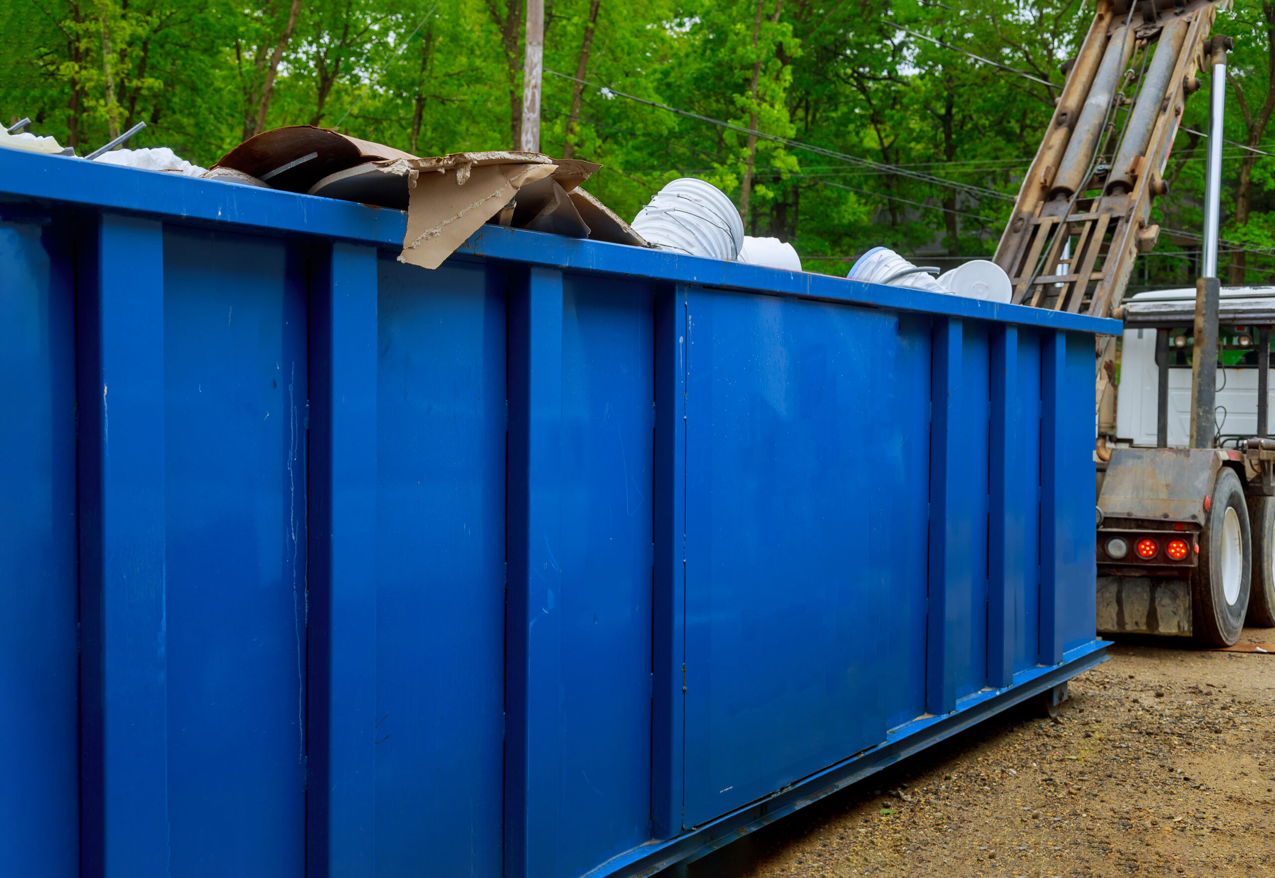 A roll-off dumpster staged at a back-of-store loading area beside palletized bulky items awaiting removal
