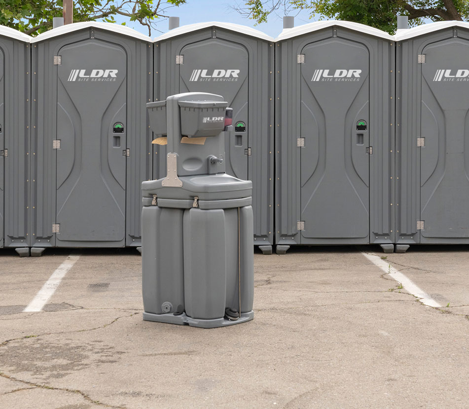 A row of portable restroom units staged at an active construction site.