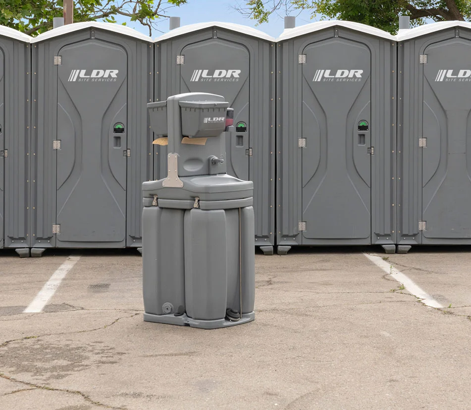A row of portable restroom units staged at an active construction site.
