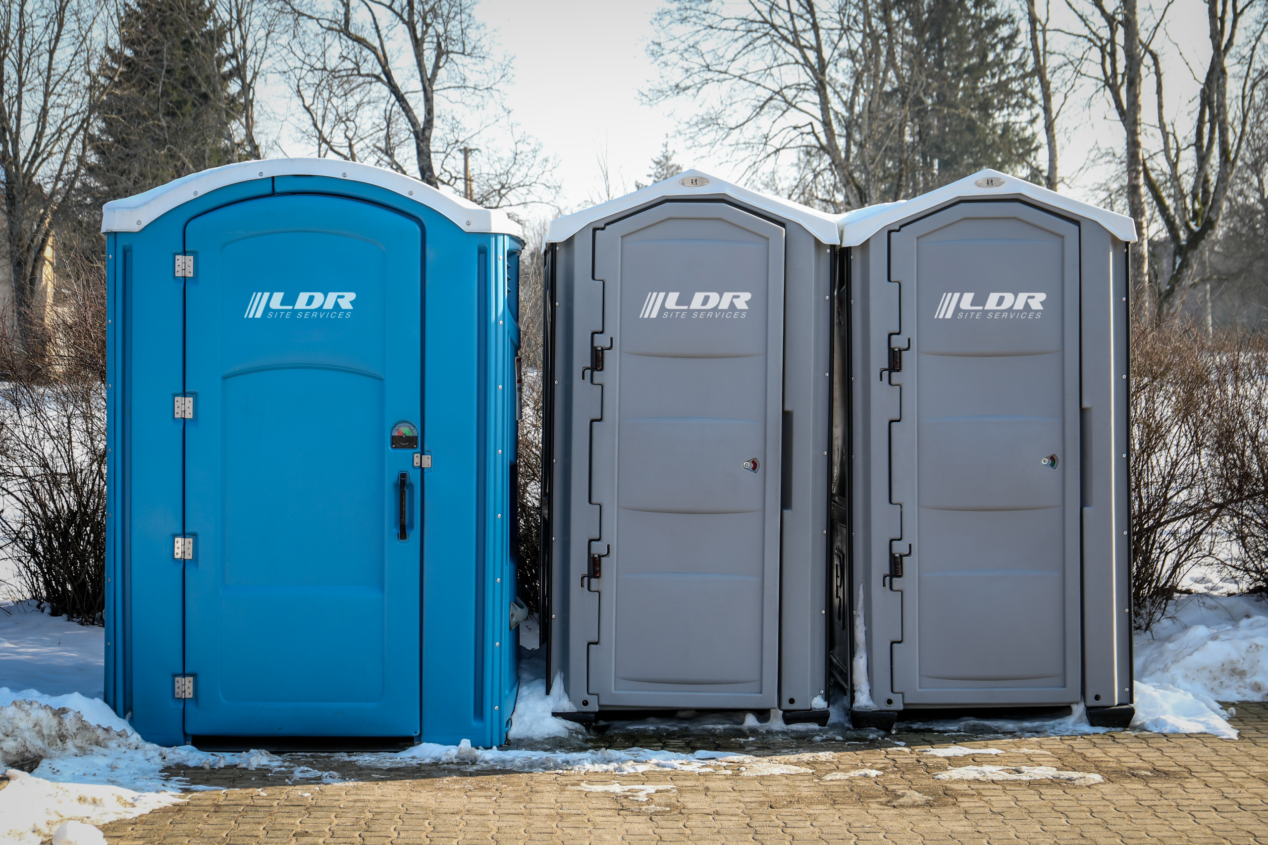 Portable restrooms and a handwash station staged on ground protection mats at an event site.